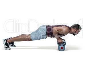 Muscular man doing push ups with kettlebells