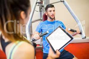 Trainer working with athlete at weights machine