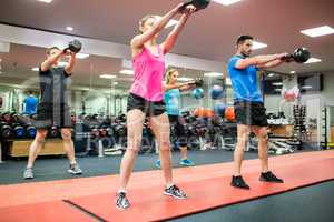 Fit people swinging kettlebell weights