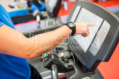 Man adjusting the settings of a treadmill