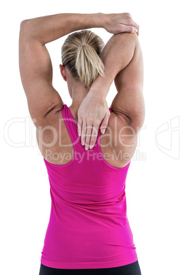 Rear view of muscular woman stretching her arm