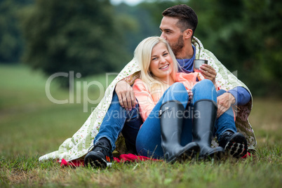 Happy couple sitting under blanket