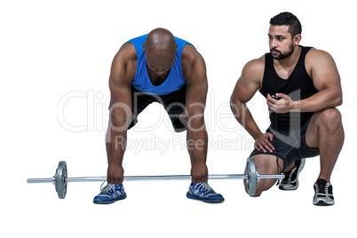 Man lifting barbell with trainer