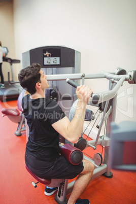 Fit man using weights machine for arms