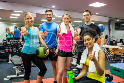 Fit people smiling at camera in weights room