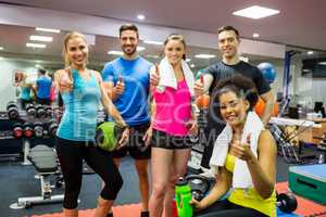 Fit people smiling at camera in weights room