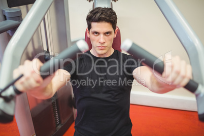 Fit man using weights machine for arms