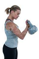 Serious muscular woman lifting kettlebell