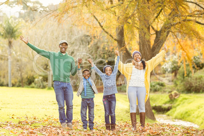 Portrait of a young smiling family with arms raised