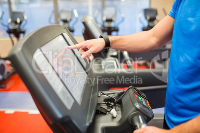 Man adjusting the settings of a treadmill