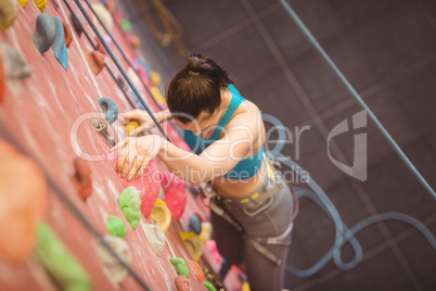 Woman climbing up rock wall