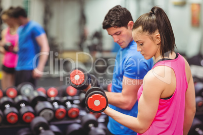 Woman lifting dumbbells with her trainer