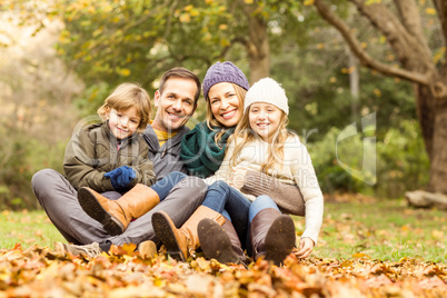 Smiling young family sitting in leaves