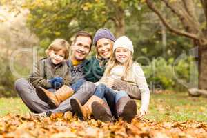 Smiling young family sitting in leaves