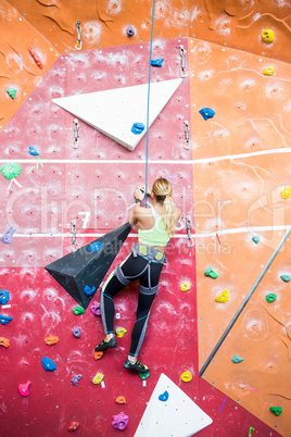 Fit blonde rock climbing indoors