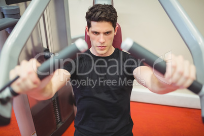 Fit man using weights machine for arms Fit man using weights machine for arms