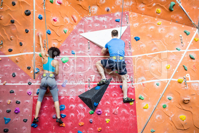 Fit couple rock climbing indoors