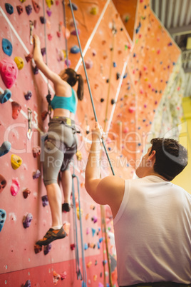 Instructor guiding woman on rock climbing wall