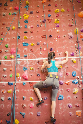 Woman climbing up rock wall