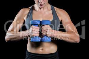 Muscular woman lifting heavy dumbbells