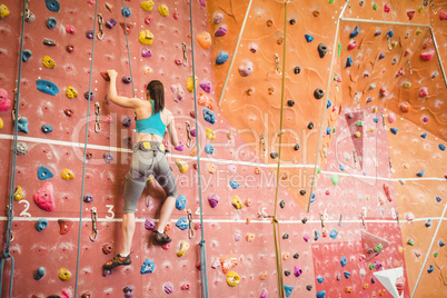 Woman climbing up rock wall