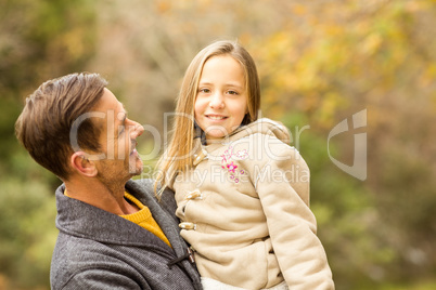 Happy father carrying his cute daughter on an autumns day