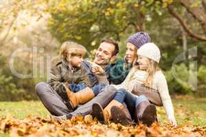 Smiling young family sitting in leaves