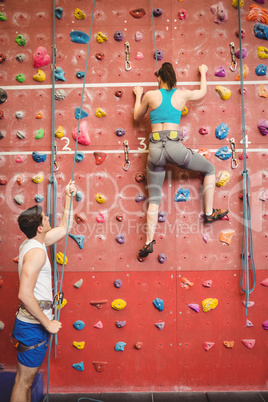 Instructor guiding woman on rock climbing wall