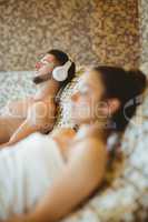 Man wearing headphones and woman lying down together