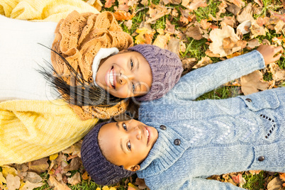 Young mother with her daughter lying in leaves