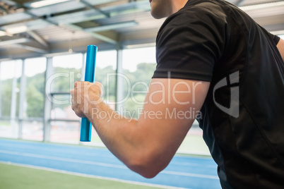 Fit man running on track with baton
