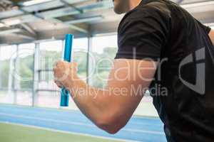 Fit man running on track with baton