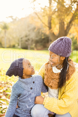 Young mother with her daughter sitting in leaves