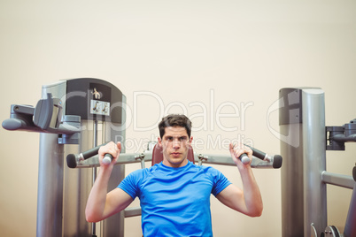 Fit man using weights machine for arms