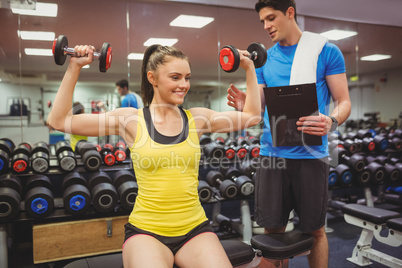 Woman lifting dumbbells with her trainer