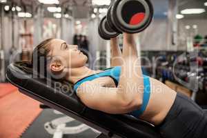 Smiling woman lifting dumbbells while lying down