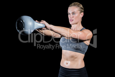 Muscular woman swinging heavy kettlebell