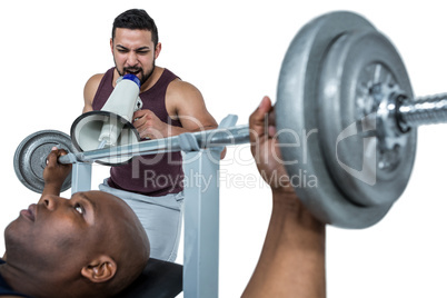 Trainer helping muscular man to lift the barbell