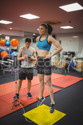 Fit woman measuring her jump with trainer