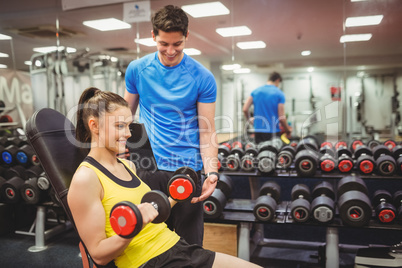 Woman lifting dumbbells with her trainer