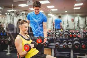 Woman lifting dumbbells with her trainer