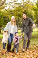 Smiling young family walking in leaves