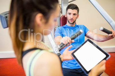 Trainer working with athlete at weights machine