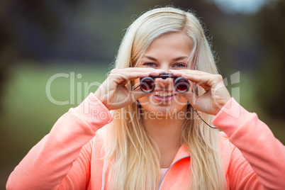 Happy blonde looking through binoculars