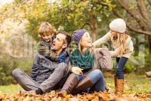 Smiling young family sitting in leaves