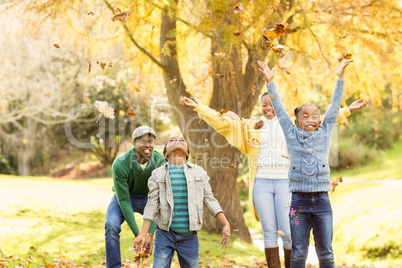 Young smiling family throwing leaves around