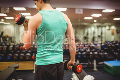 Fit man lifting heavy black dumbbells