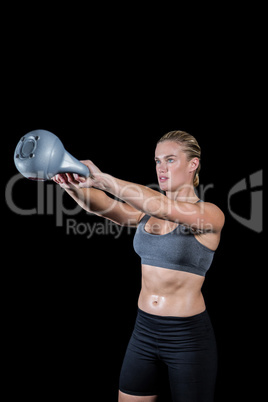 Muscular woman swinging heavy kettlebell