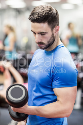 Fit man lifting heavy black dumbbell