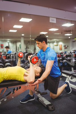 Woman lifting dumbbells with her trainer